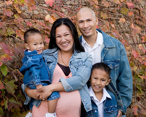 A happy family of four posing with matching jean jackets in a fall setting.