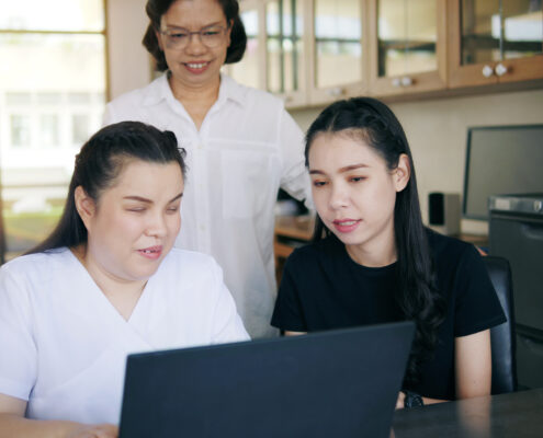 low visually disabled woman using a laptop with family behind her