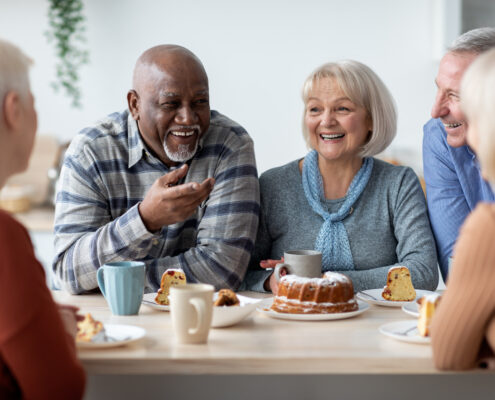 group of elderly people enjoying drinking tea with cake