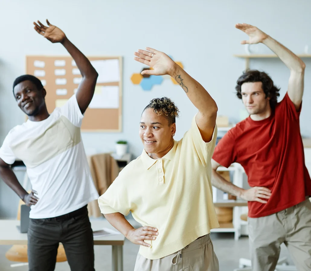 Three people stretching in an office setting.