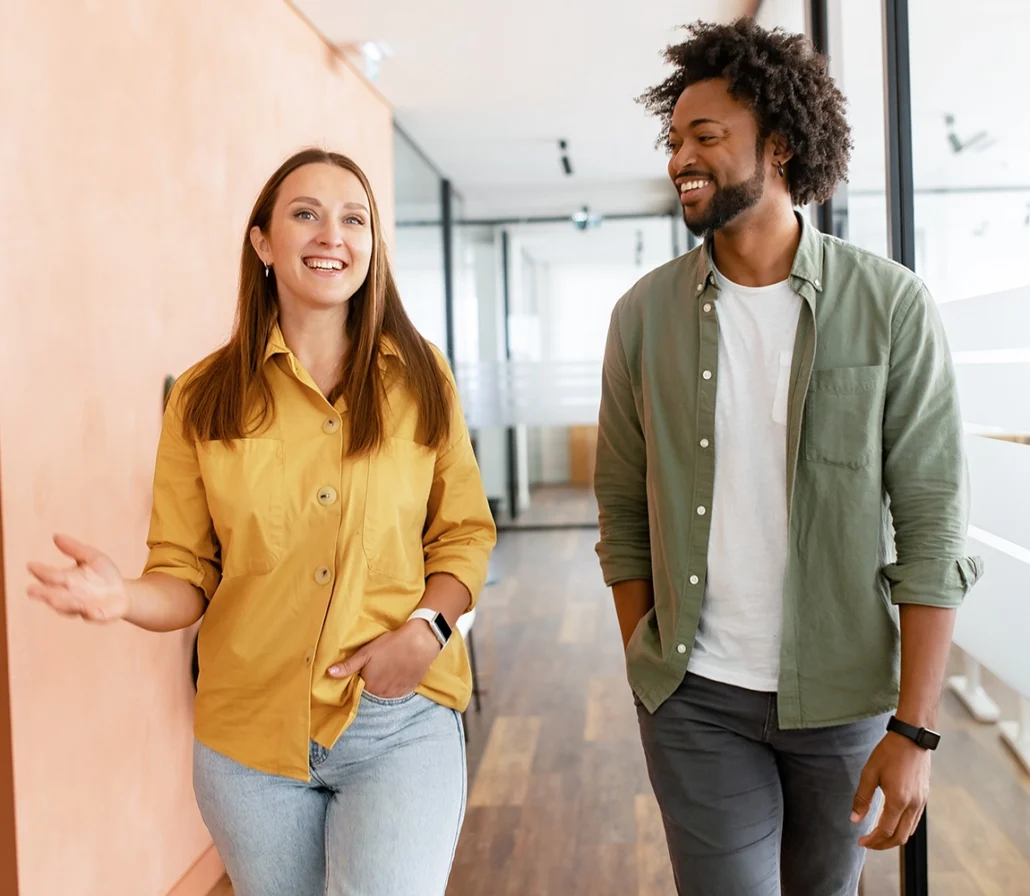 Two people walking down a hallway talking.