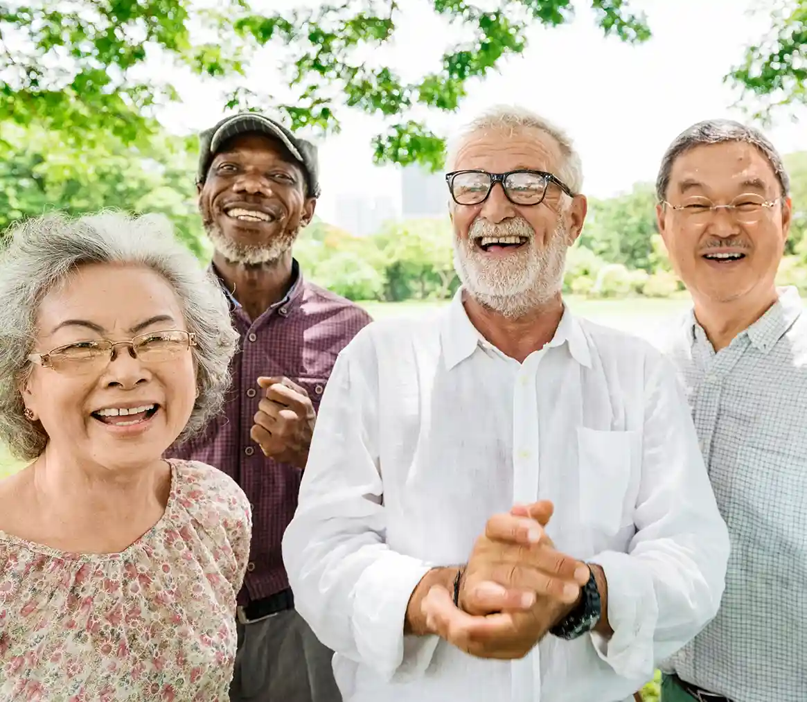Four older people standing outside laughing